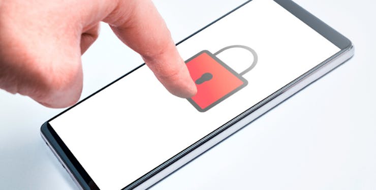 Bloqueio do WhatsApp: celular com imagem de cadeado e mão tentando desbloquear