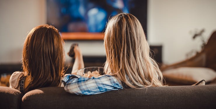 Mulheres sentadas no sofá assistindo televisão