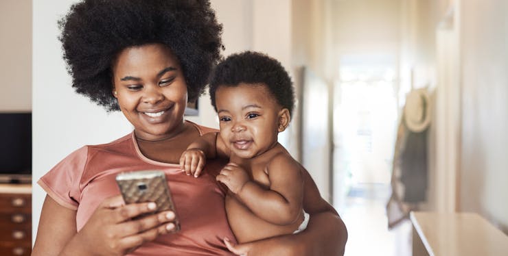 Nono dígito: mulher acrescenta números na agenda do celular com filho no colo