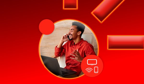 homem falando no celular e mexendo no computador