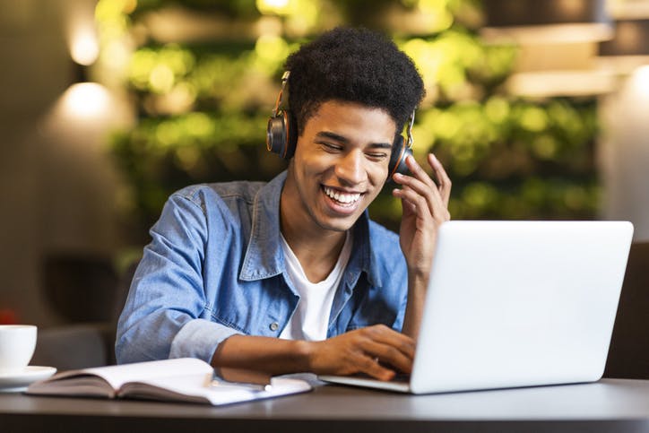 Menino escutando música e estudando no notebook com a Claro Internet
