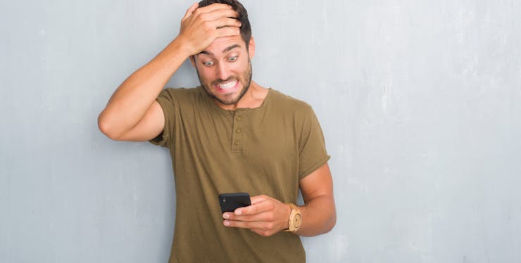 Homem indignado com um celular na mão