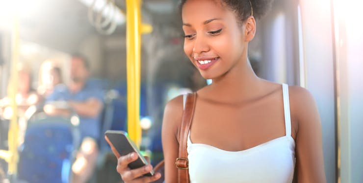 mulher em um onibus mexendo no celular