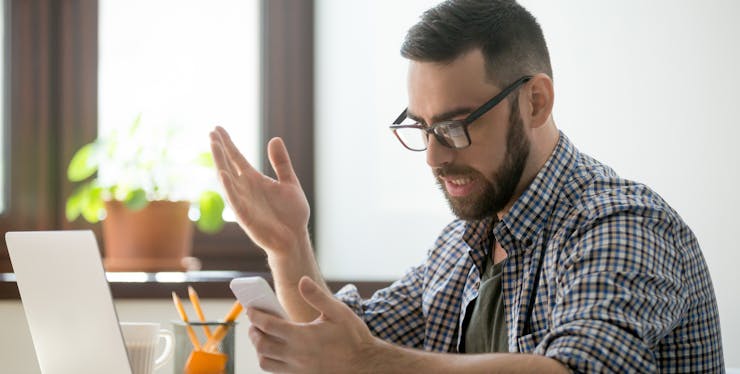Homem ruivo barbado irritado com o celular