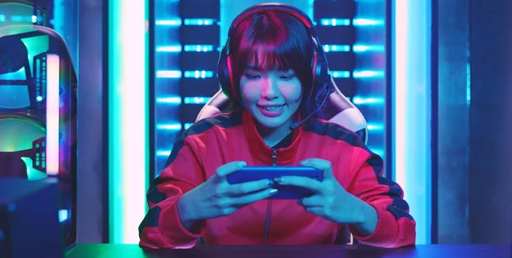 mulher sentada em cadeira gamer jogando no celular