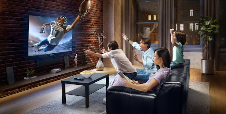 grupo de pessoas comemorando enquanto assistem jogo na tv