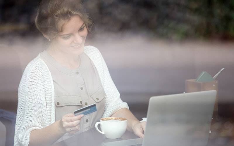 Senhora usando notebook com cartão em mãos
