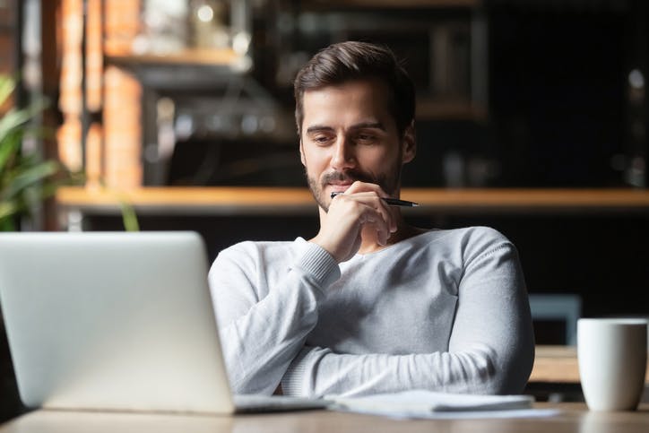 homem com expressão de dúvida olhando para notebook