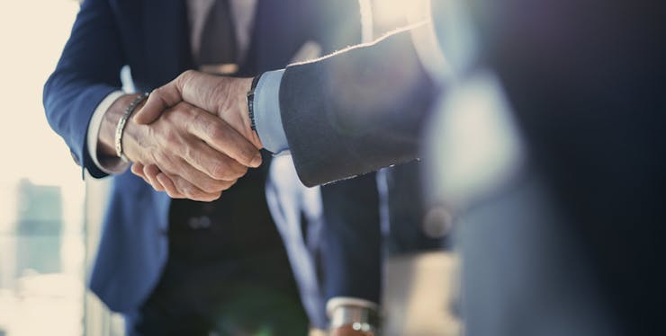 Aperto de mão entre dois homens de terno