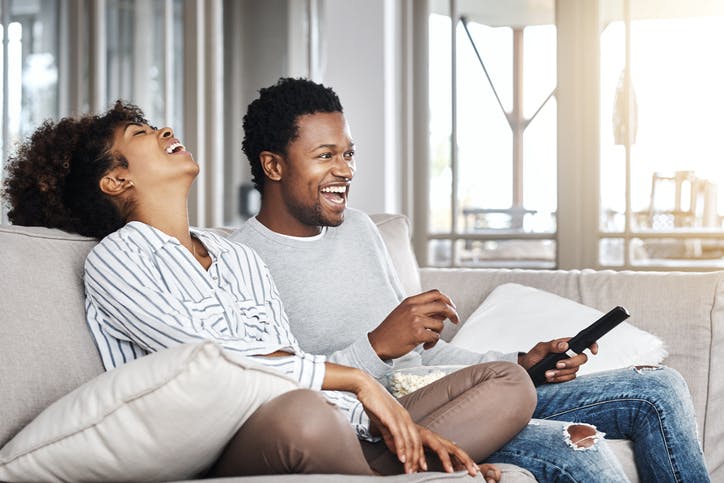 Homem e mulher sorrindo e assistindo TV