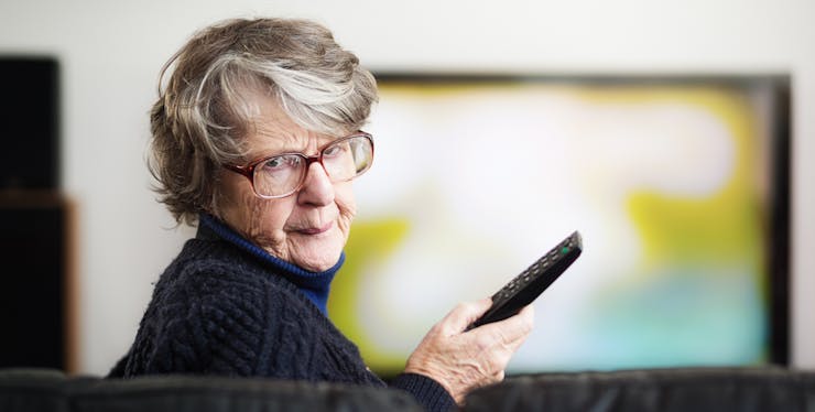 mulher idosa indignada com um controle de TV na mão