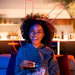 mulher sorrindo assistindo tv e comendo pipoca