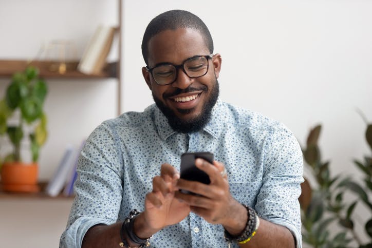 Homem sorrindo digitando em seu celular
