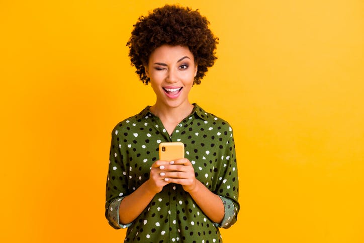 Mulher piscando com celular na mão