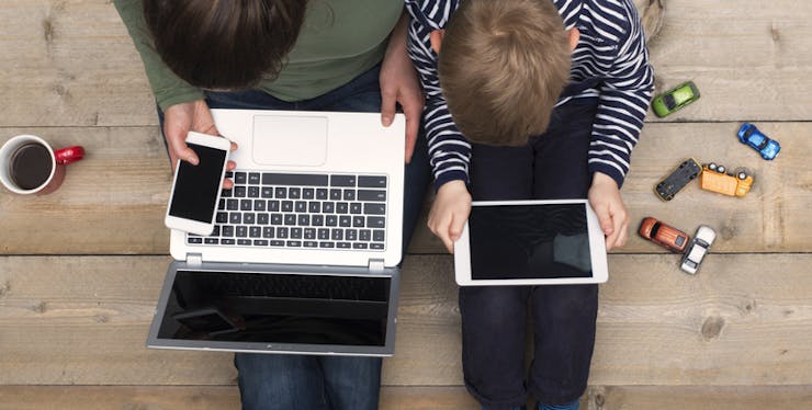 Mãe e filho utilizando conectados no tablet e notebook.