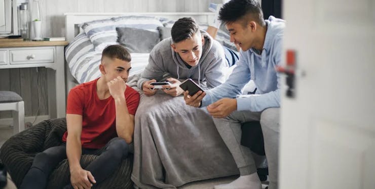 Três adolescentes em um quarto olhando um celular