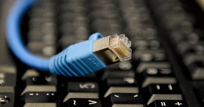 Cabo de Internet banda larga em cima de teclado escuro.