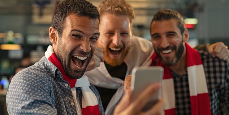 três homens assistindo algo no celular
