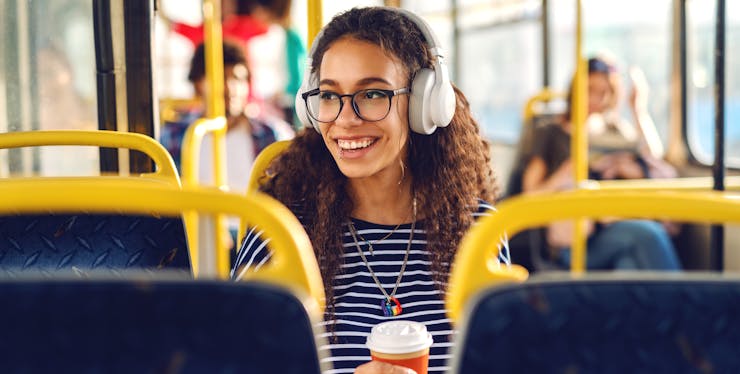 mulher sorrindo ouvindo musica no ônibus