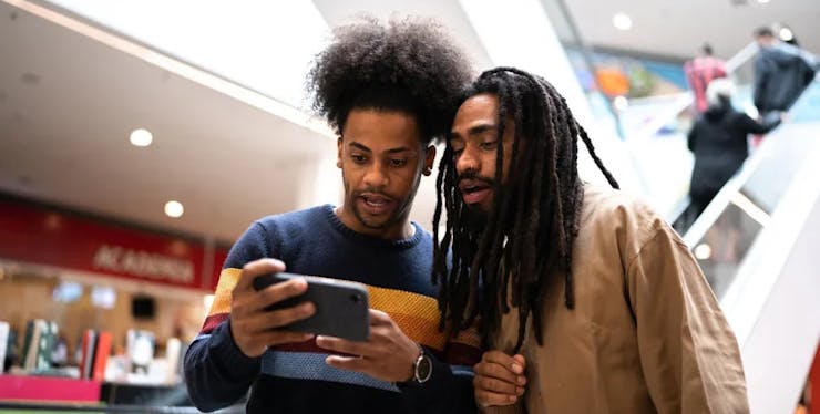 dois homens olhando o celular em uma shopping