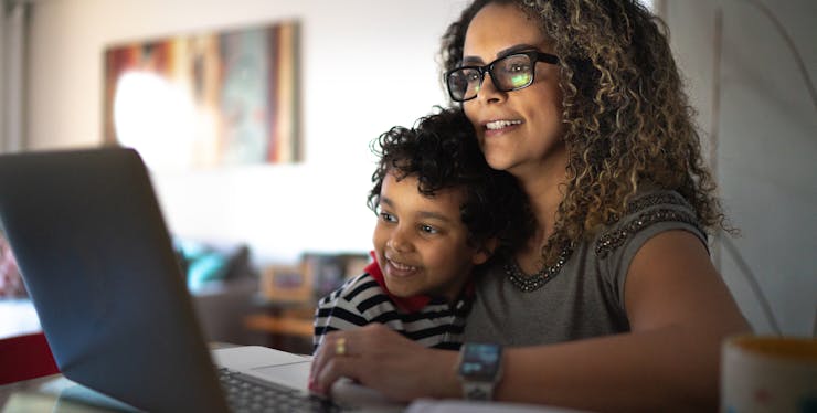 Mulher com uma criança no colo olhando o computador