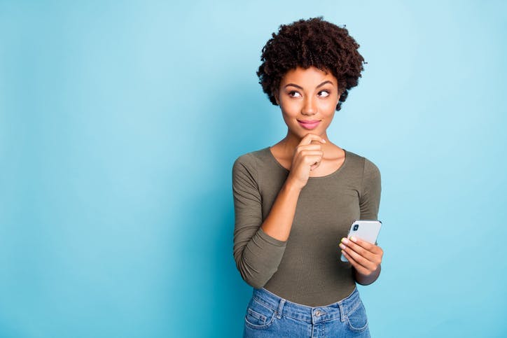 Mulher em dúvida segurando celular