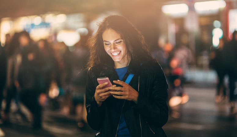 Mulher sorrindo enquanto usa o celular