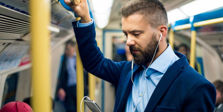 homem usa fones de ouvido enquanto usa o celular no transporte público