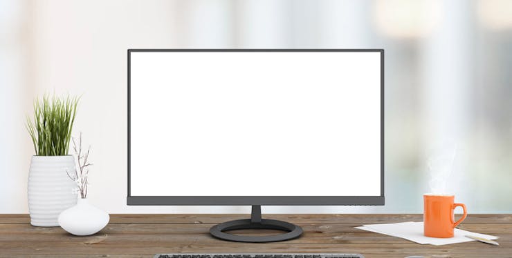 Monitor de um PC com a tela branca em cima de uma mesa