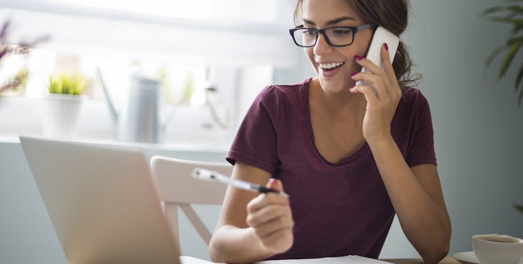 Mulher falando no celular e olhando o computador 