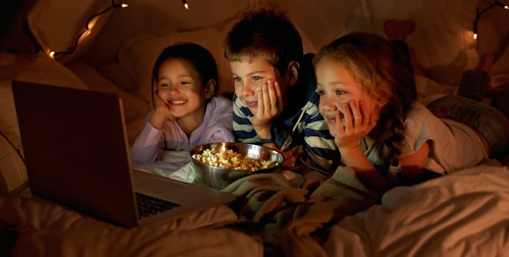 Crianças comendo pipoca e assistindo uma série no Amazon Prime.