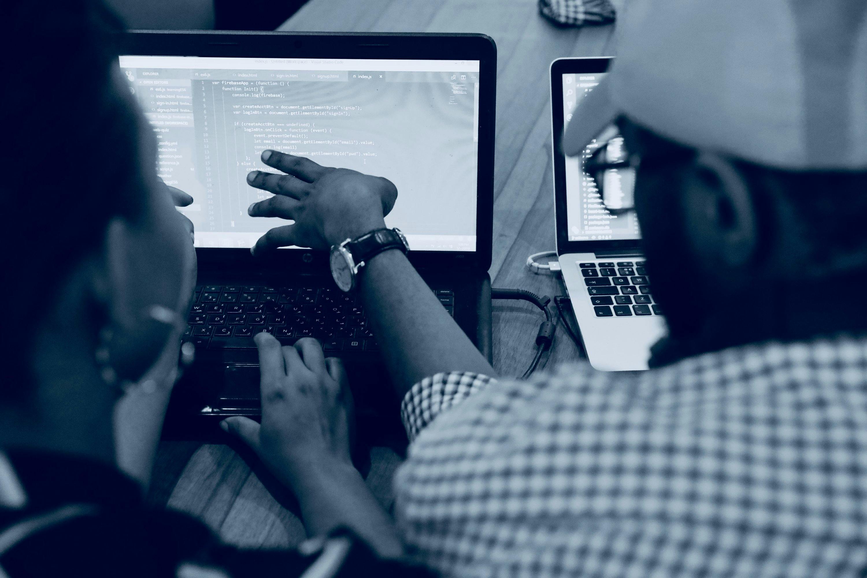 Two people working collaboratively on a laptop