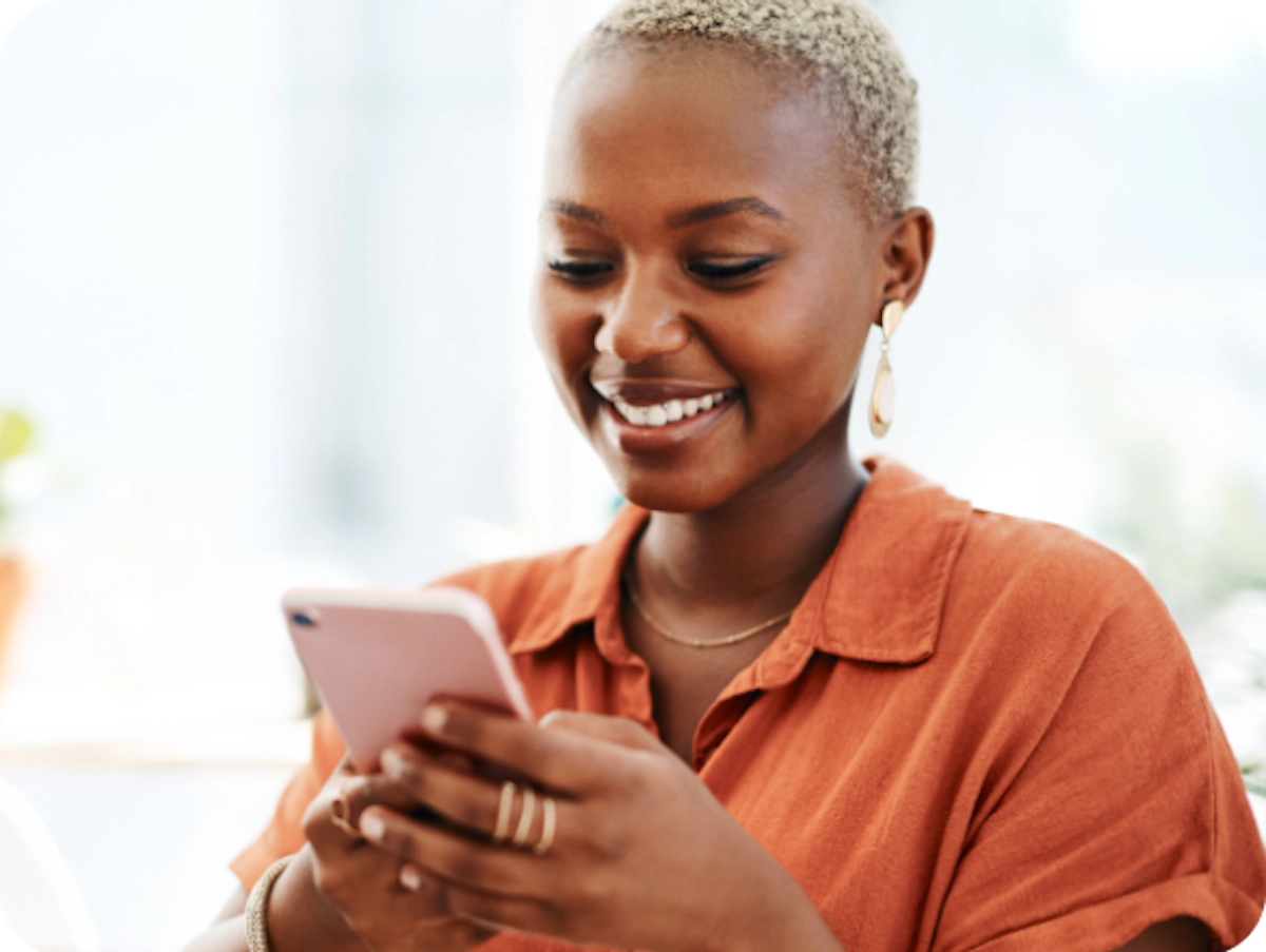 Moça negra de laranja mexendo no celular
