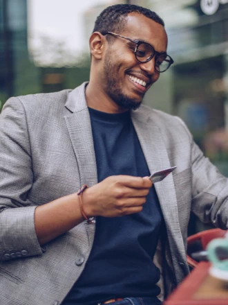 Imagem de homem sorrindo em um café com o seu cartão PortoBank em mãos
