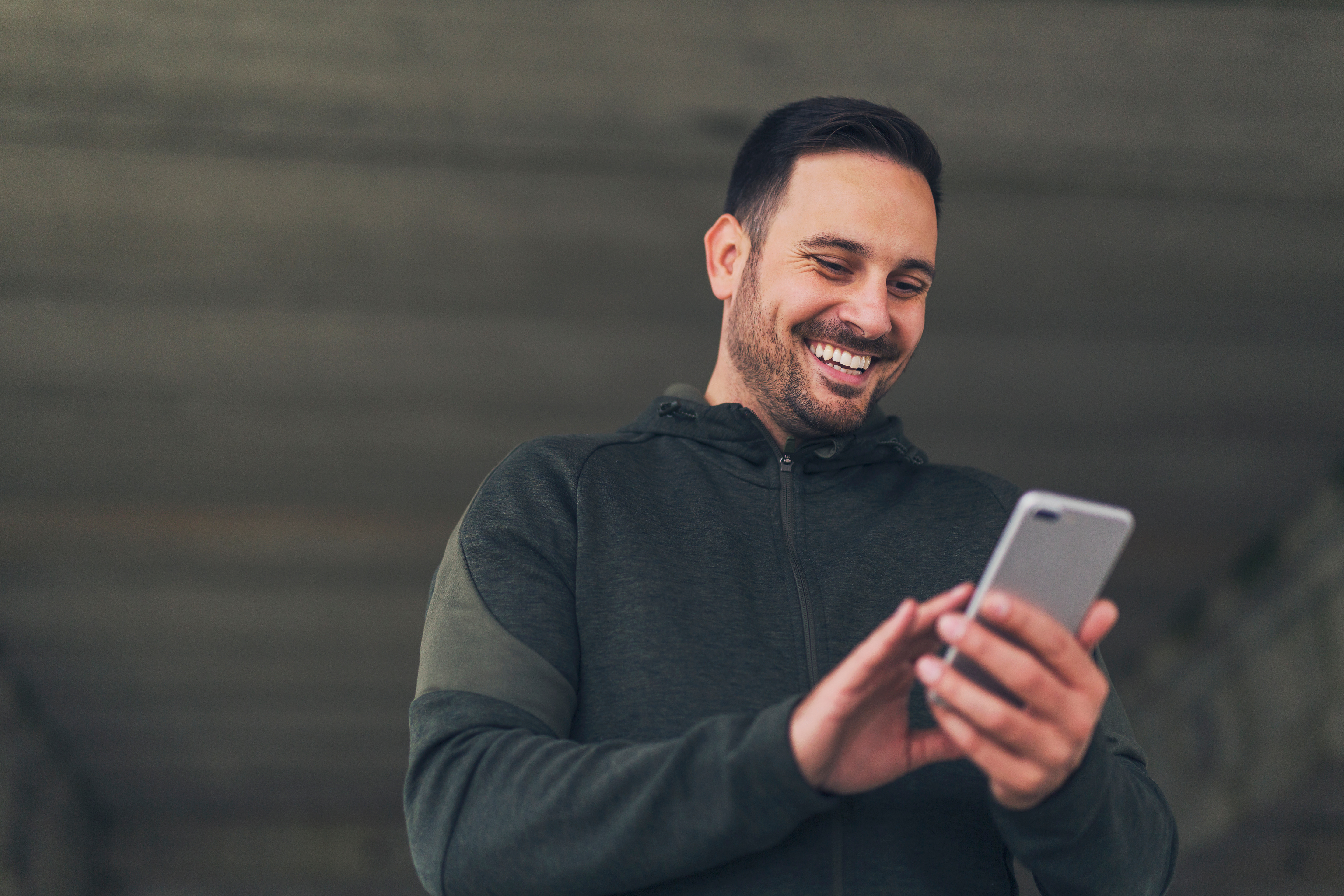 Homem com roupa escura segurando celular