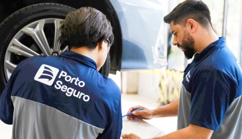 Especialistas da Porto, um homem e uma mulher, analisam juntos o serviço de um veículo no centro automotivo.