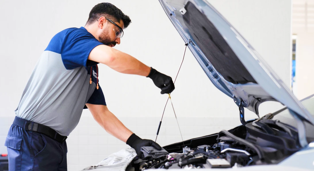 Mecânico verifica o nível de óleo do motor de um carro durante um check-up.