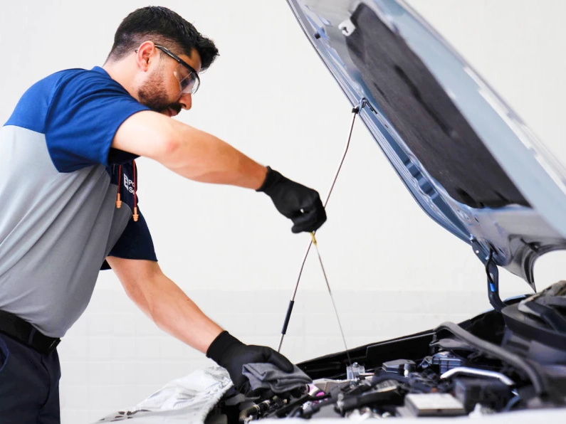 Mecânico verifica o nível de óleo do motor de um carro durante um check-up.