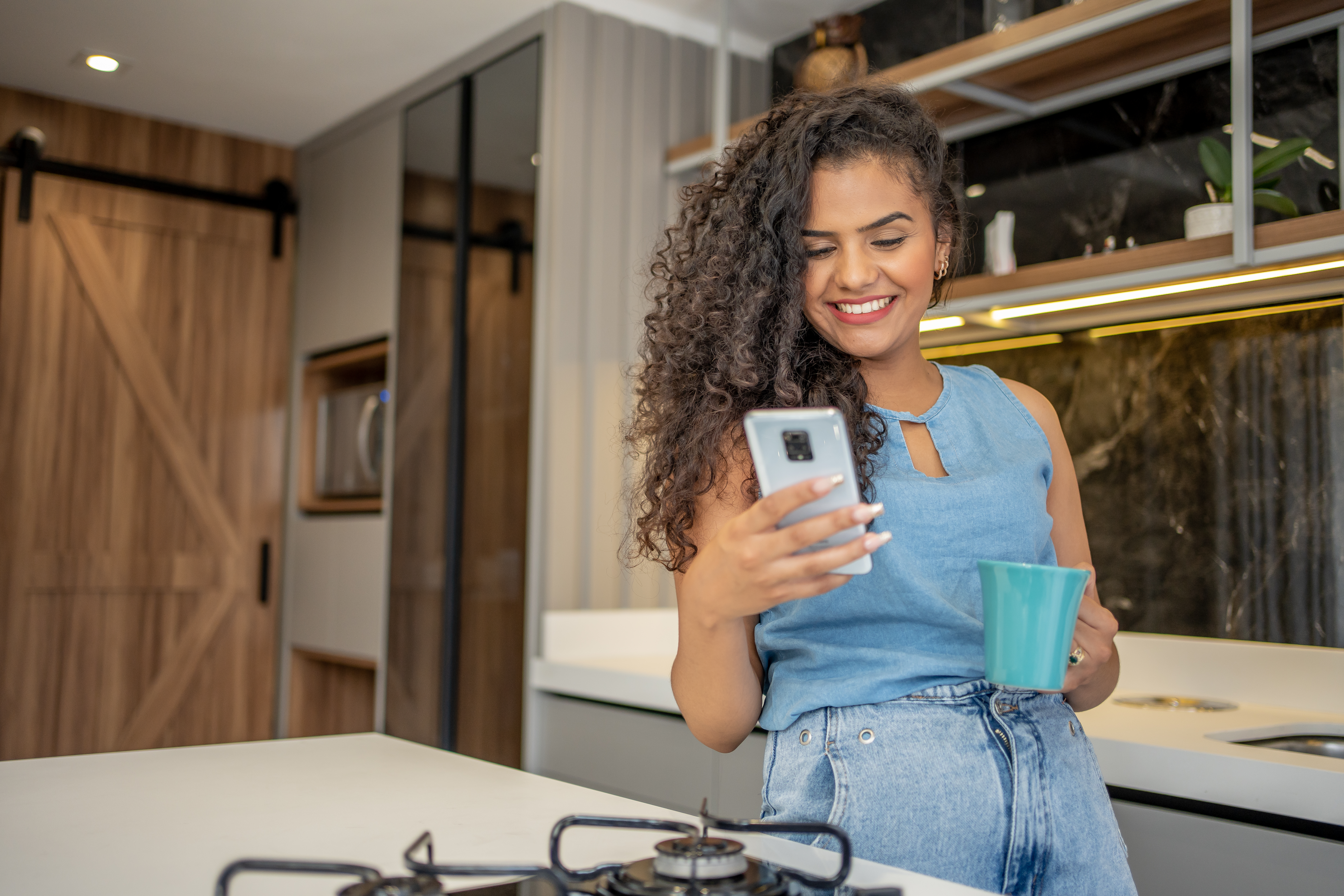 Mulher segurando o celular em uma cozinha