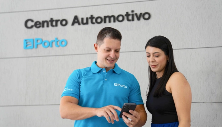 Especialista em um Centro Automotivo, mostra um detalhe no celular para uma cliente.