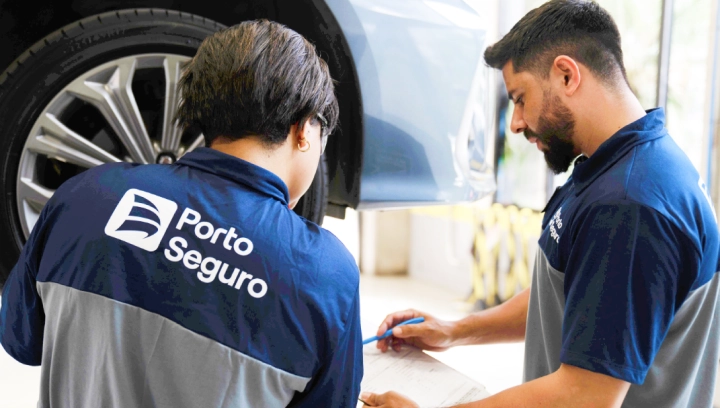 Especialistas da Porto, um homem e uma mulher, analisam juntos o serviço de um veículo no centro automotivo.