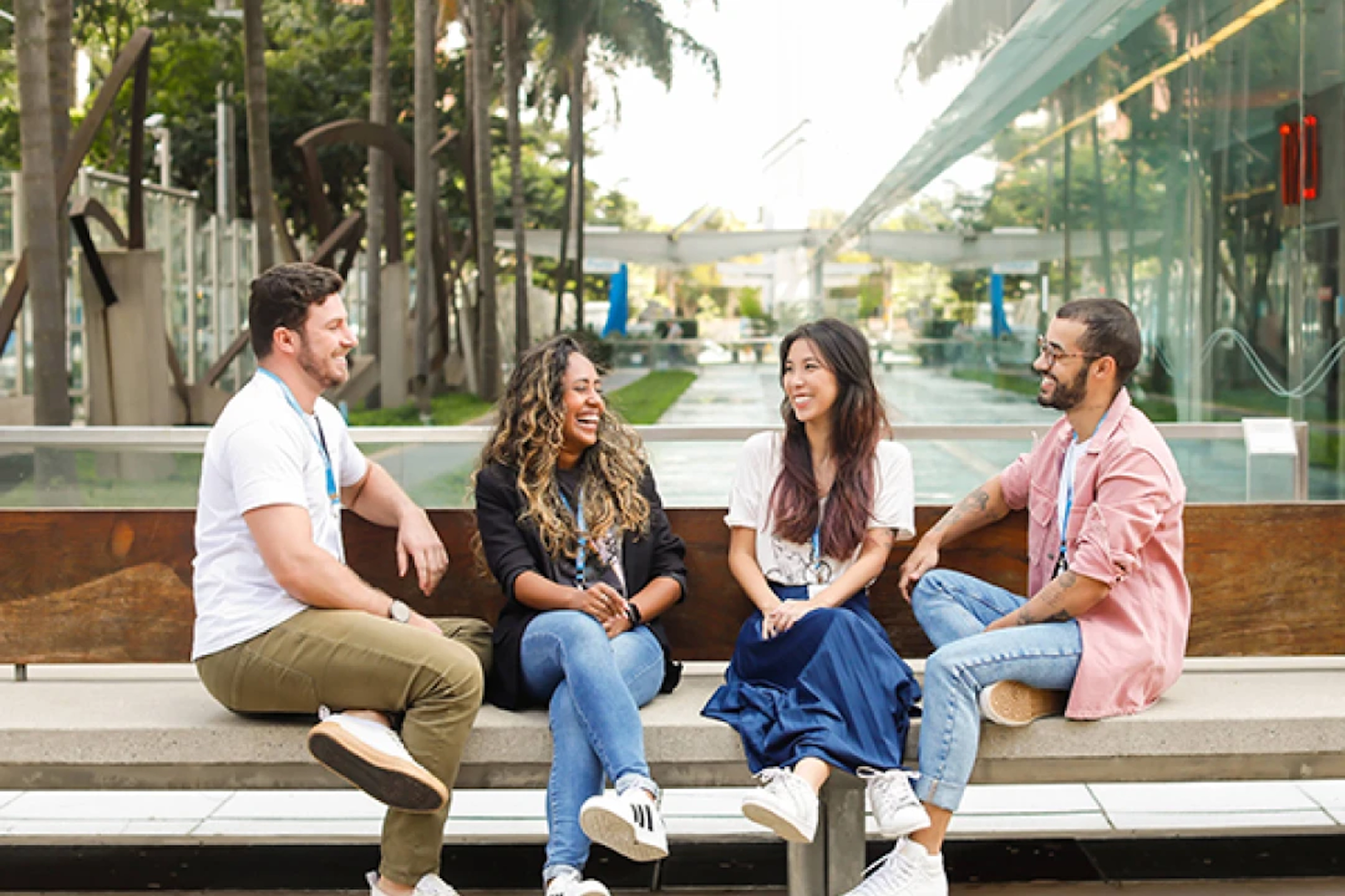 dois homens e duas mulheres, sentados em um banco, todos estão sorrindo