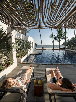 Mulheres deitadas no sofá relaxando em frente a piscina
