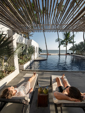 Mulheres deitadas no sofá relaxando em frente a piscina