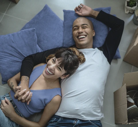 Imagem de homem e mulher sorrindo abraçados e deitados numa cama