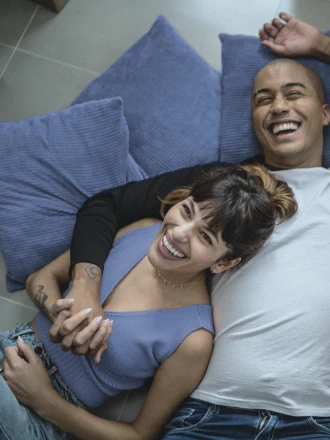 Imagem de homem e mulher sorrindo abraçados e deitados numa cama