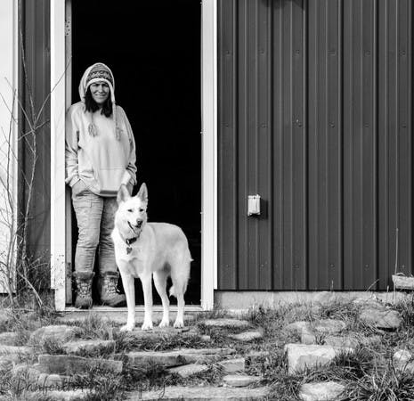 Lady in doorway looking out at white german shepherd dog outside