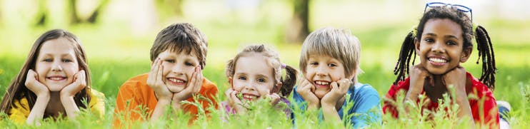5 children lying in the grass smiling