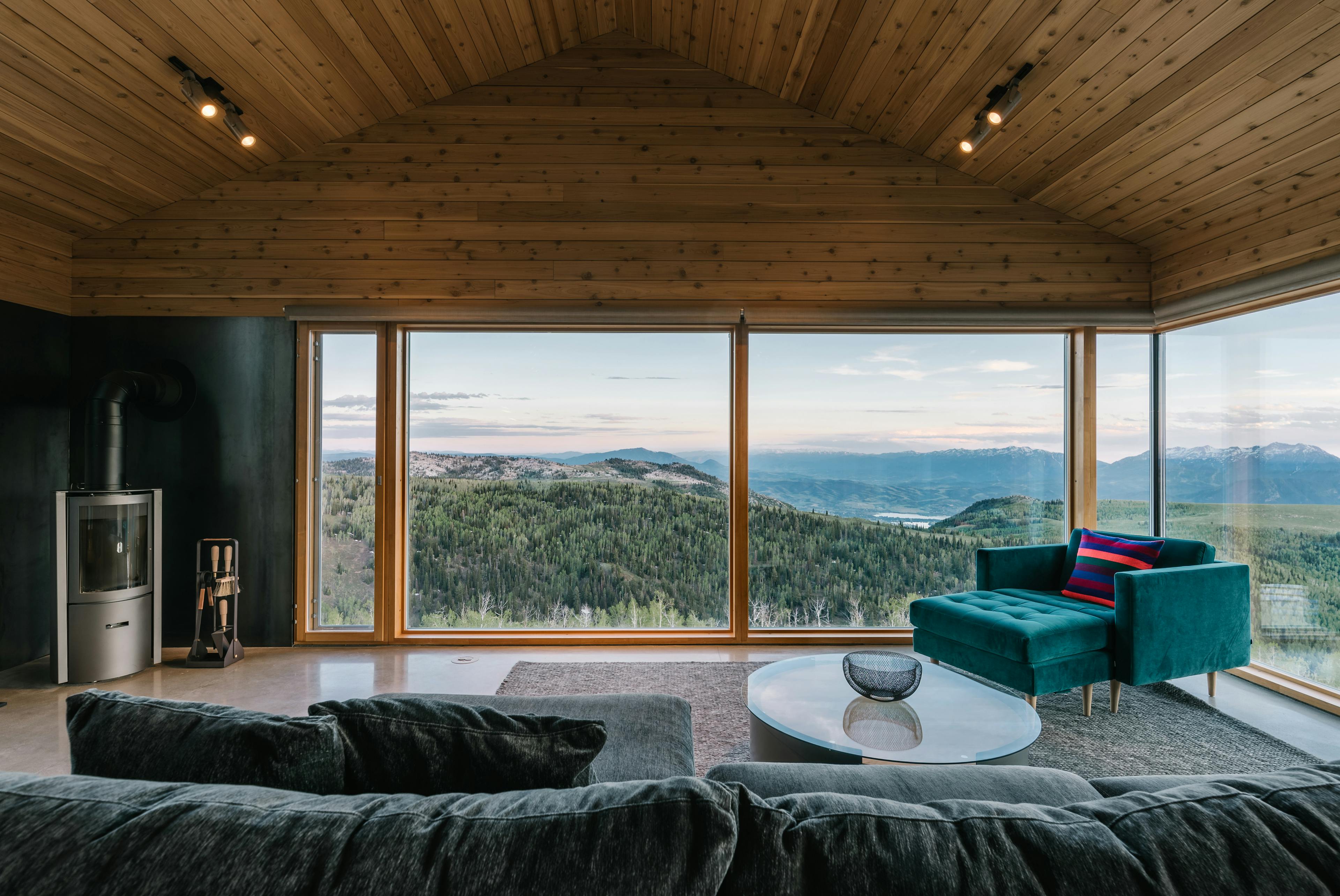 View from a modern mountain home overlooking forested hills and distant peaks, illustrating the setting and appeal of new Powder Haven homesites.