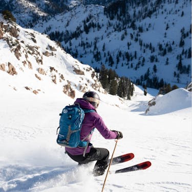 A skier descends into a steep chute